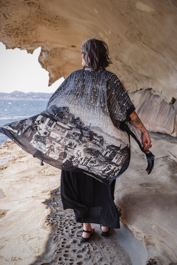 Model wearing a celestial flowy kimono duster in bamboo & wood blend viscose ft. the 1833 Leonid meteor shower in a dreamy star-filled night sky - Market of Stars.