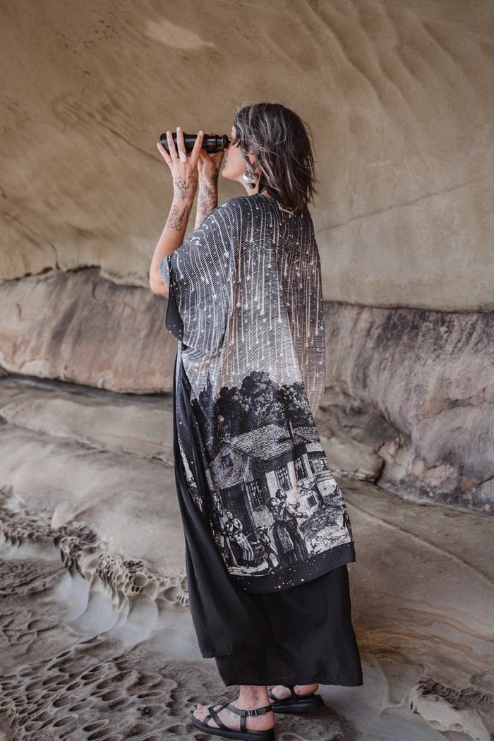 Model wearing a celestial flowy kimono duster in bamboo & wood blend viscose ft. the 1833 Leonid meteor shower in a dreamy star-filled night sky - Market of Stars.