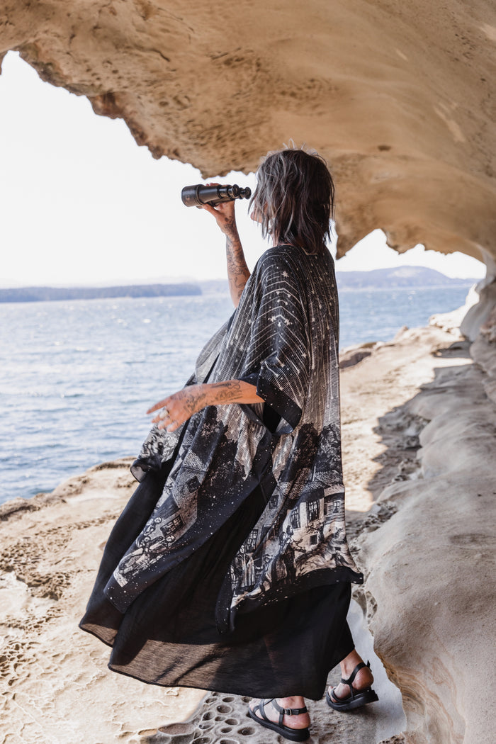 Model wearing a celestial flowy kimono duster in bamboo & wood blend viscose ft. the 1833 Leonid meteor shower in a dreamy star-filled night sky - Market of Stars.