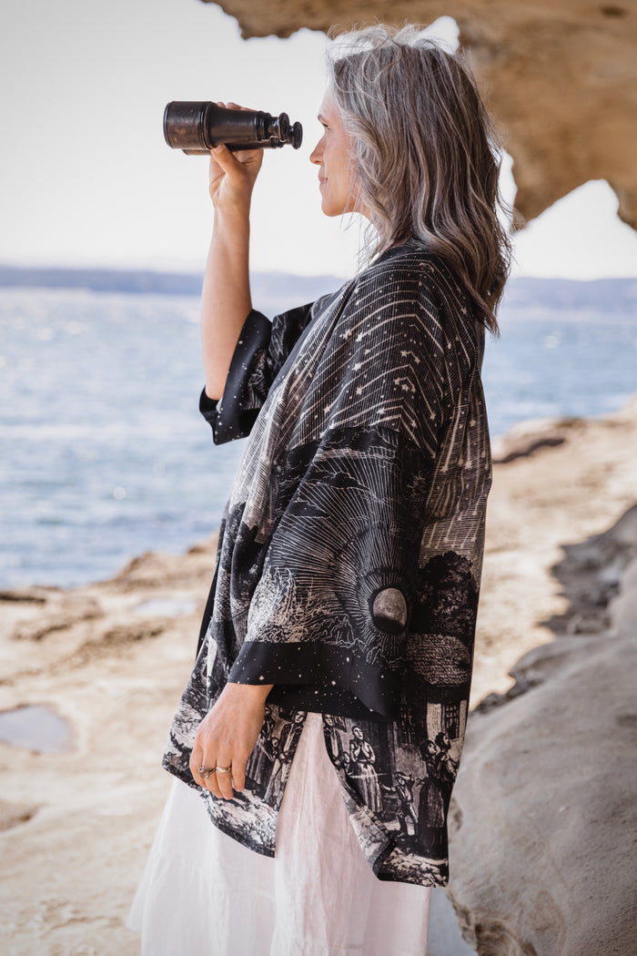 Model wearing a celestial mid-length kimono duster in bamboo & wood blend viscose ft. the 1833 Leonid meteor shower in a dreamy star-filled night sky - Market of Stars.