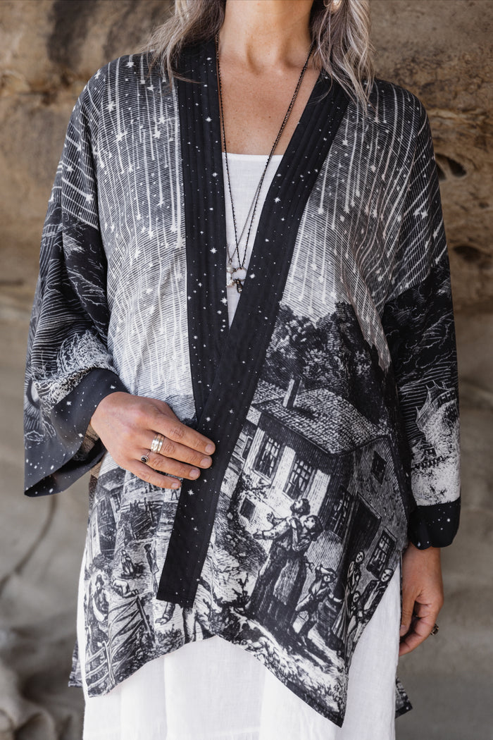 Model wearing a celestial mid-length kimono duster in bamboo & wood blend viscose ft. the 1833 Leonid meteor shower in a dreamy star-filled night sky - Market of Stars.