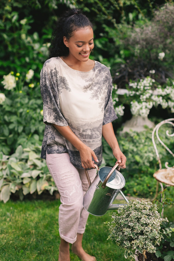 Model wearing the Still I Rise Luxe Tee with wide scoop neck and soft bamboo-based viscose, featuring vintage landscape etching and an inspiring message – Market of Stars