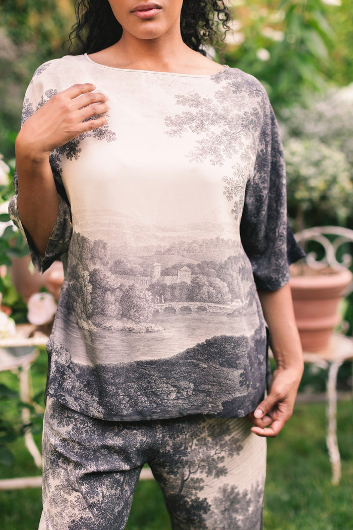 Model wearing the Still I Rise Luxe Tee with wide scoop neck and soft bamboo-based viscose, featuring vintage landscape etching and an inspiring message – Market of Stars
