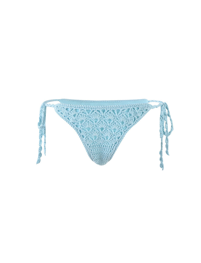 The SUNNIVA BIKINI BOTTOM in baby blue from TIGERMIST showcases a detailed crochet pattern and adjustable tie string closures on both sides. It is elegantly displayed against a plain white background.