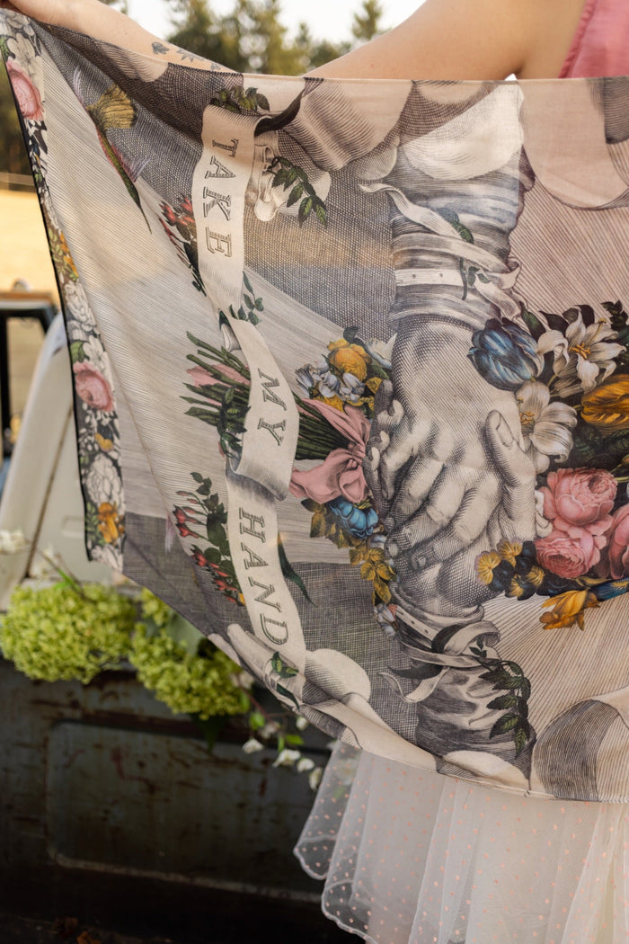 Model wearing Take My Hand scarf with 1600s hand engraving of clasped hands, a painted heart, florals and sun rays – Market of Stars