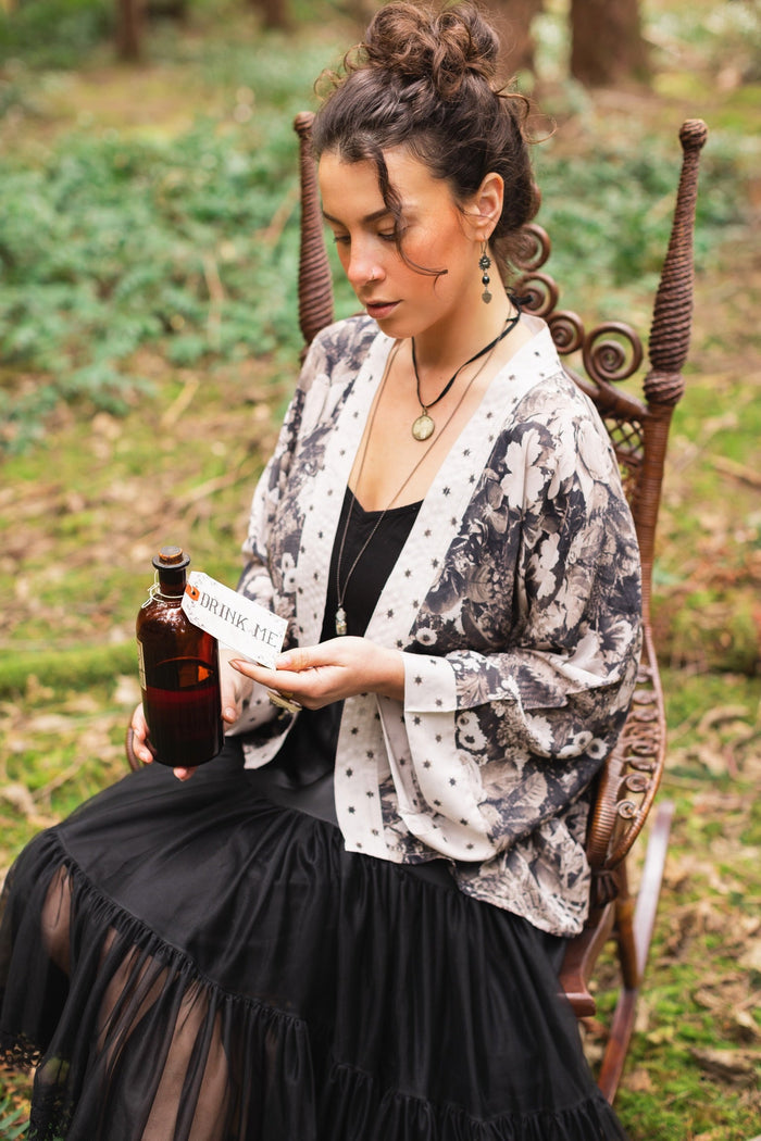 Model wearing Looking Glass Cropped Kimono featuring grown-up Alice Liddell, rare Victorian botanicals, and celestial star and moon accents inspired by Wonderland – Market of Stars.