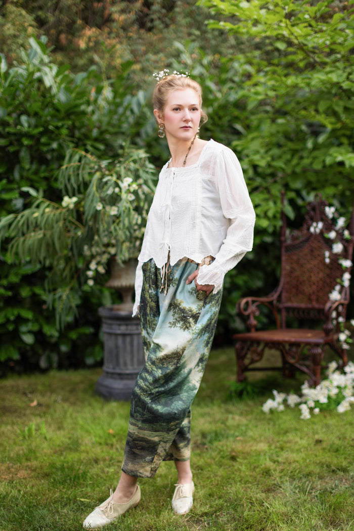 Model wearing a cropped length linen blend pant ft. vintage artwork & unicorn lorn set against a mossy-green landscape — a romantic piece for the modern dreamer - Market of Stars