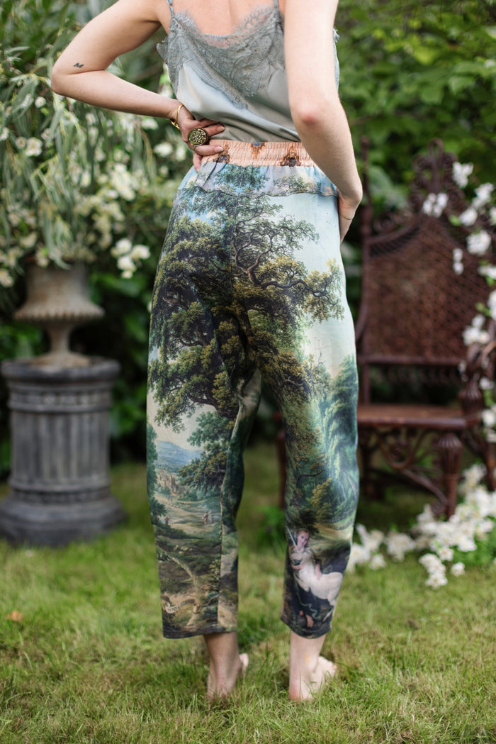 Model wearing a cropped length linen blend pant ft. vintage artwork & unicorn lorn set against a mossy-green landscape — a romantic piece for the modern dreamer - Market of Stars