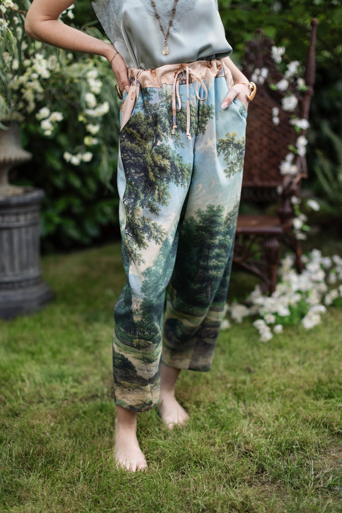 Model wearing a cropped length linen blend pant ft. vintage artwork & unicorn lorn set against a mossy-green landscape — a romantic piece for the modern dreamer - Market of Stars