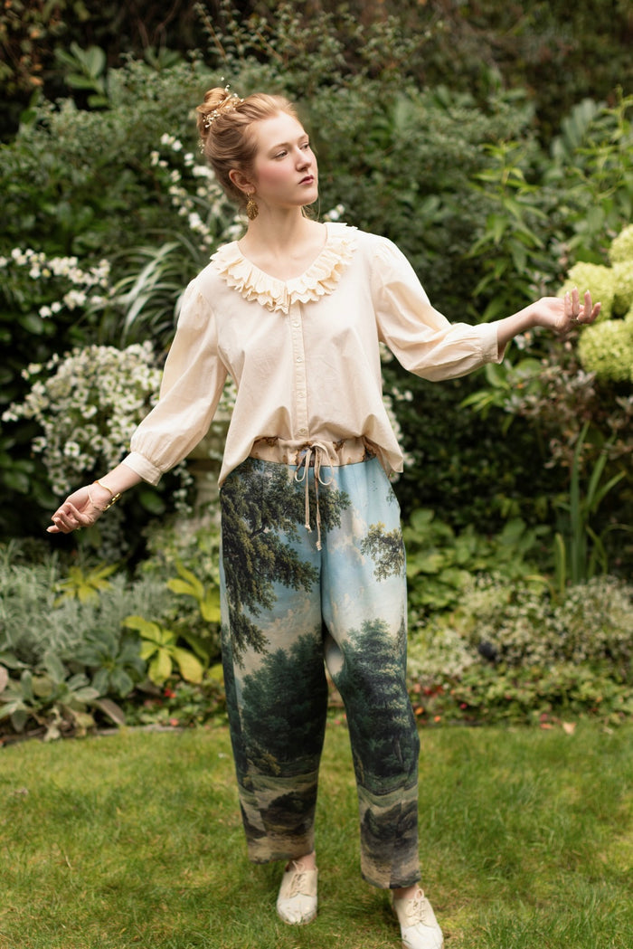 Model wearing a cropped length linen blend pant ft. vintage artwork & unicorn lorn set against a mossy-green landscape — a romantic piece for the modern dreamer - Market of Stars