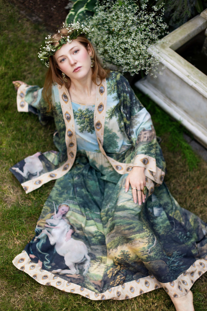 Model wearing a maxi-length slip dress ft. vintage artwork & unicorn lorn set against a mossy-green landscape — a romantic piece for the modern dreamer - Market of Stars