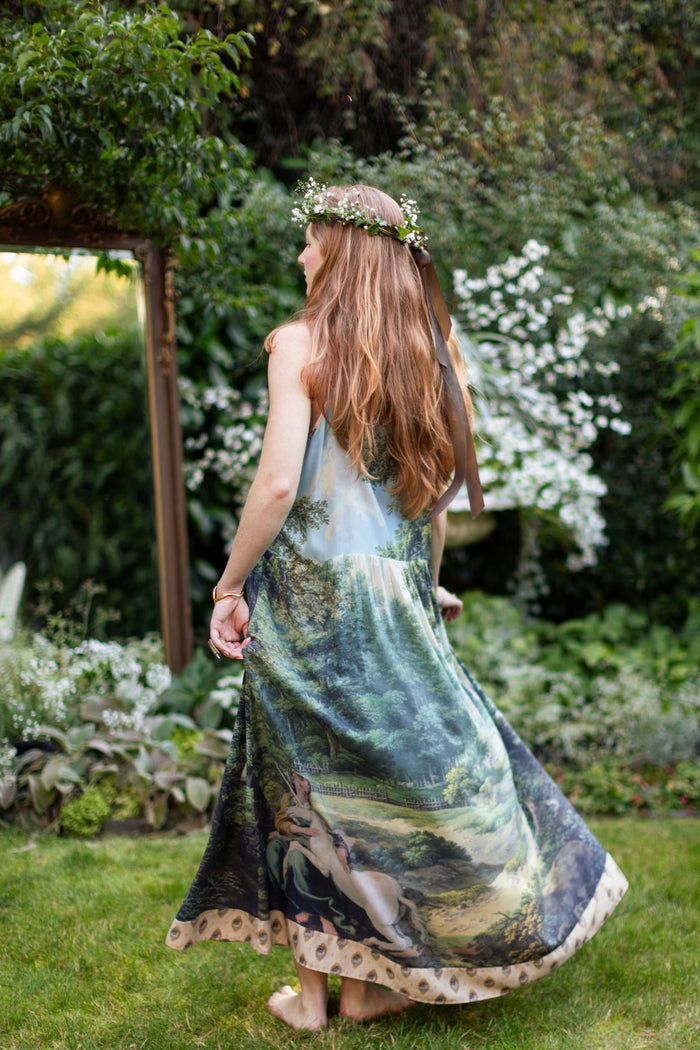 Model wearing a maxi-length slip dress ft. vintage artwork & unicorn lorn set against a mossy-green landscape — a romantic piece for the modern dreamer - Market of Stars
