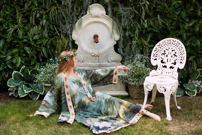 Model wearing a maxi-length slip dress ft. vintage artwork & unicorn lorn set against a mossy-green landscape — a romantic piece for the modern dreamer - Market of Stars