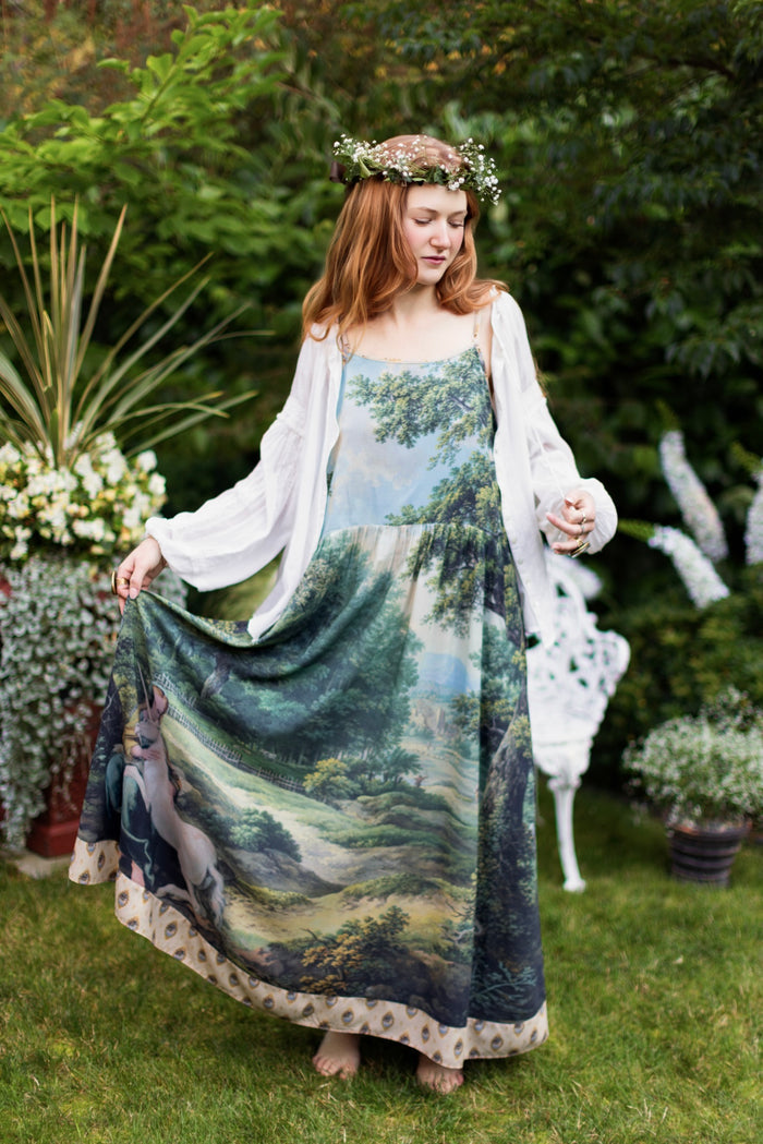 Model wearing a maxi-length slip dress ft. vintage artwork & unicorn lorn set against a mossy-green landscape — a romantic piece for the modern dreamer - Market of Stars