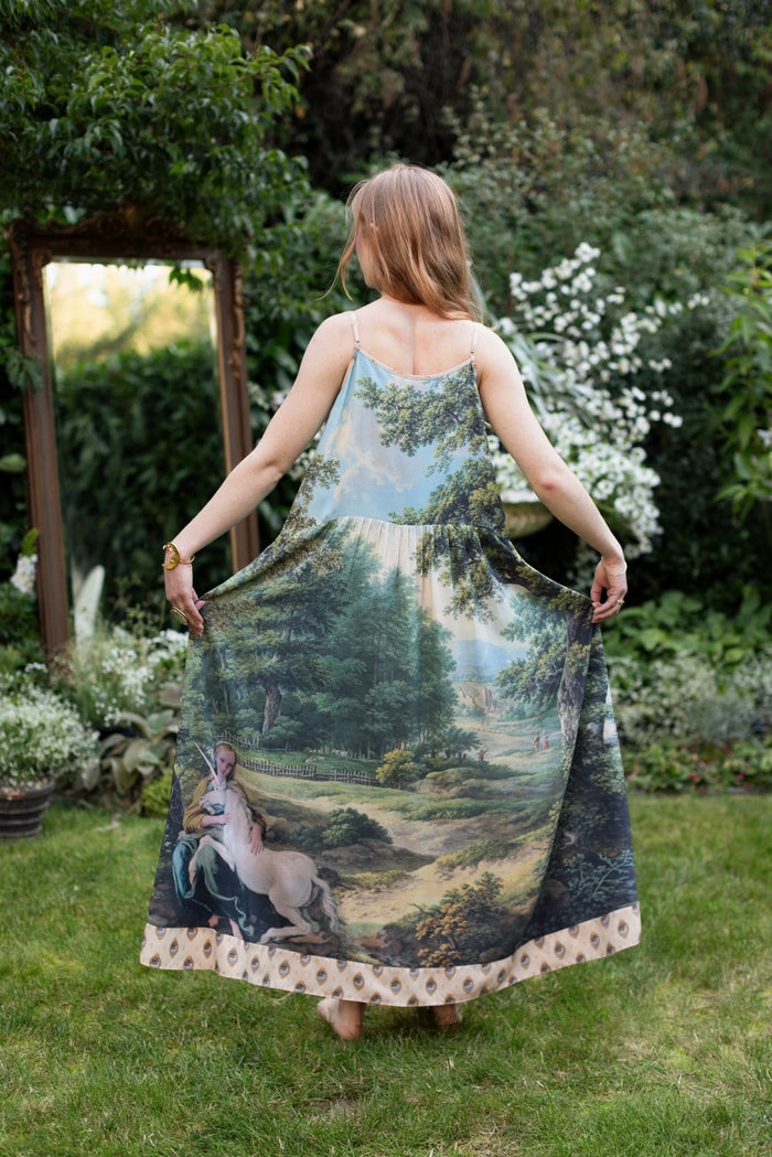 Model wearing a maxi-length slip dress ft. vintage artwork & unicorn lorn set against a mossy-green landscape — a romantic piece for the modern dreamer - Market of Stars