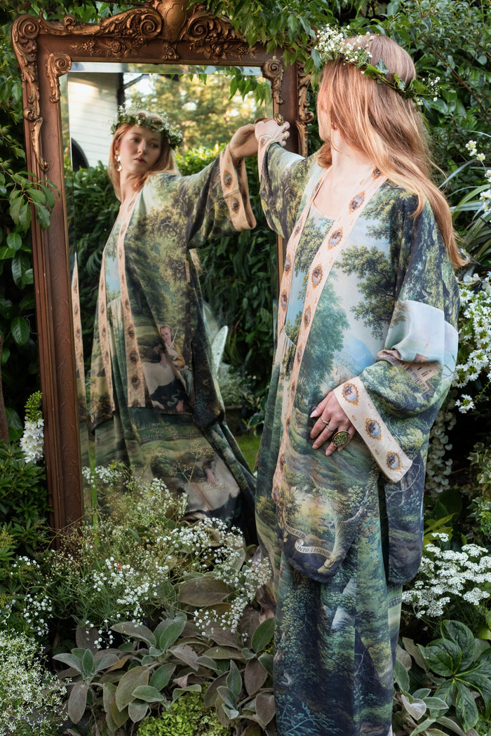 Model wearing a mid-length duster ft. vintage artwork & unicorn lorn set against a mossy-green landscape — a romantic piece for the modern dreamer - Market of Stars