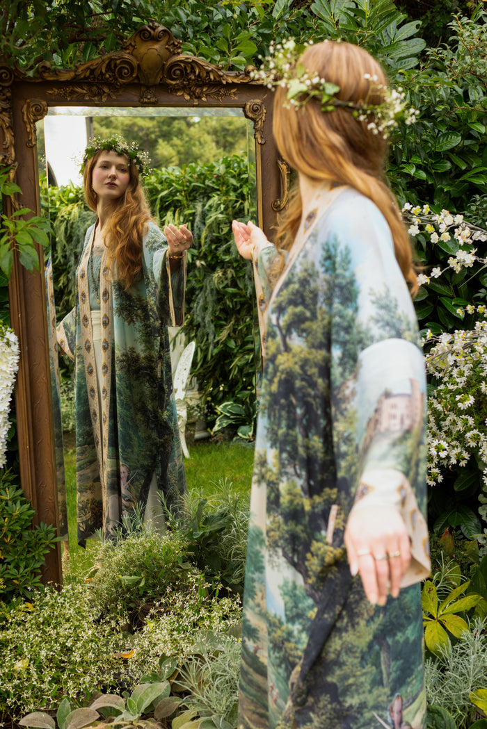 Model wearing a full-length duster ft. vintage artwork & unicorn lorn set against a mossy-green landscape — a romantic piece for the modern dreamer - Market of Stars