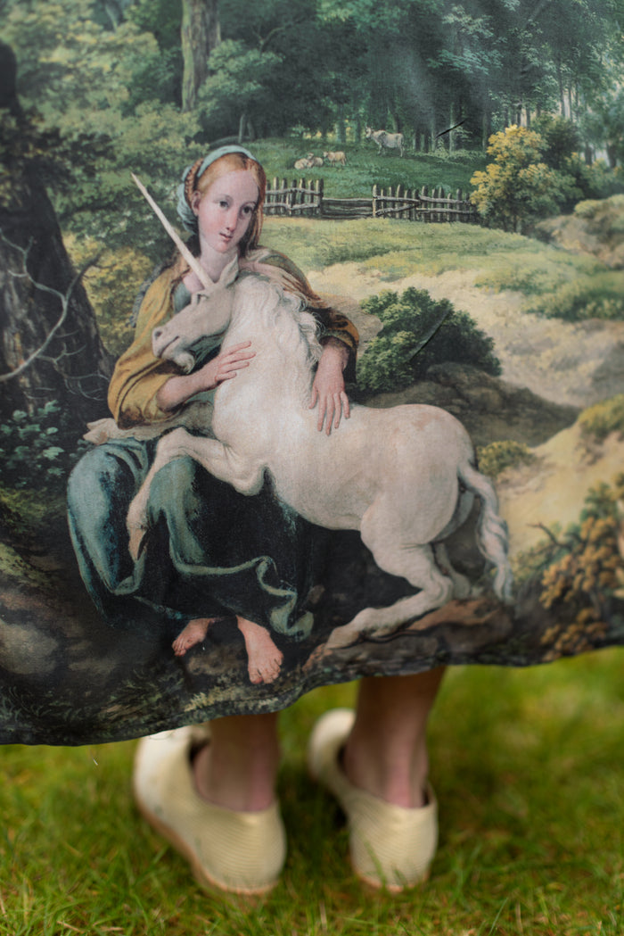 Model wearing a full-length duster ft. vintage artwork & unicorn lorn set against a mossy-green landscape — a romantic piece for the modern dreamer - Market of Stars