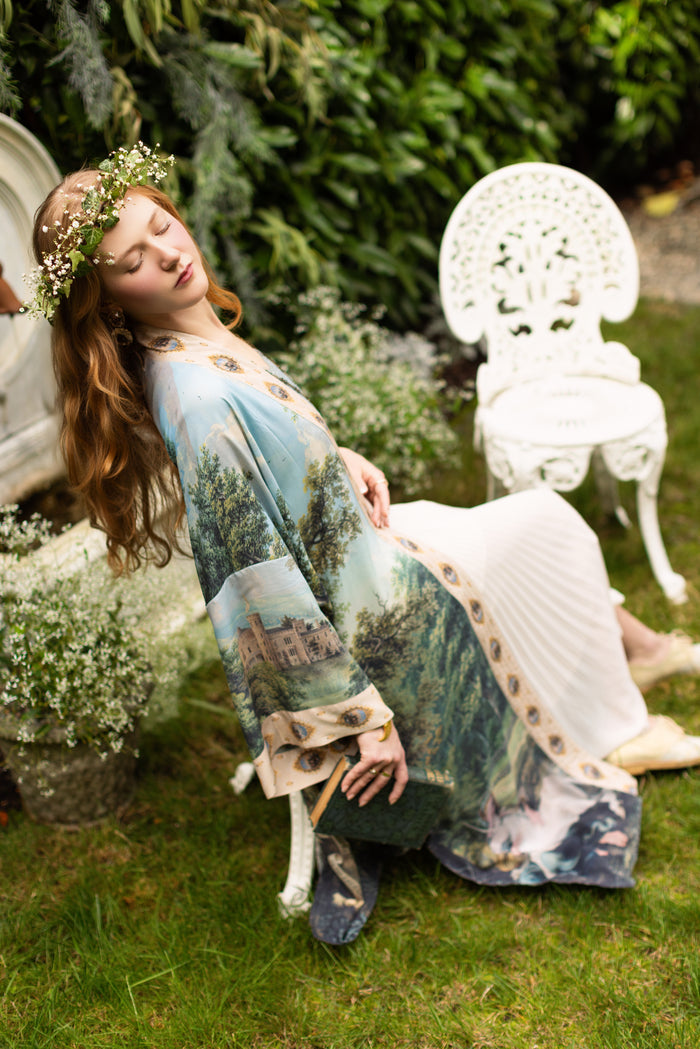 Model wearing a full-length duster ft. vintage artwork & unicorn lorn set against a mossy-green landscape — a romantic piece for the modern dreamer - Market of Stars
