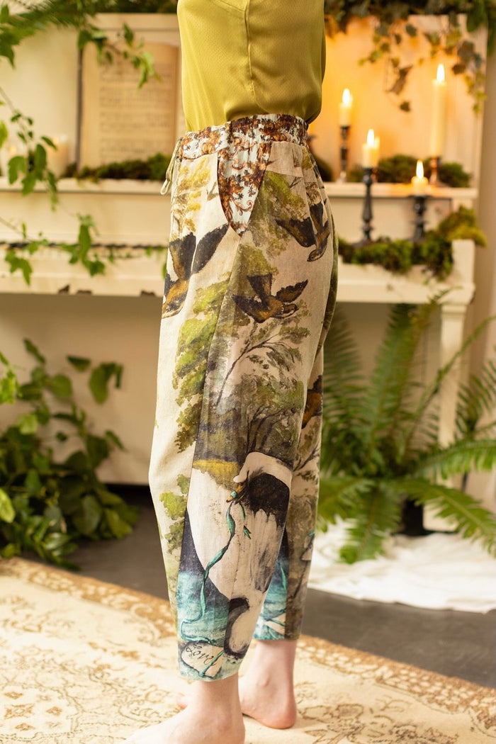 Model wearing Theatre of Dreams Artist Pants with lantern-hem silhouette featuring antique landscape, swan, and painted birds by artist Jennifer Lanne