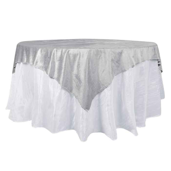 Silver tablecloth draped over a round table with a white base.