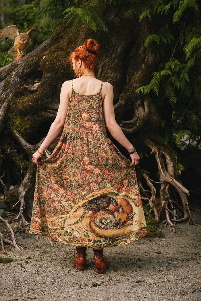 Model wearing a bamboo-viscose maxi length slip dress where even the unlikeliest of friends...a fox and a pheasant...find warmth in each other’s company. Created in collaboration with Charles van Sandwyck - Market of Stars