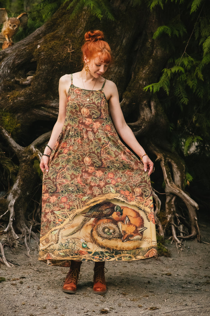 Model wearing a bamboo-viscose maxi length slip dress where even the unlikeliest of friends...a fox and a pheasant...find warmth in each other’s company. Created in collaboration with Charles van Sandwyck - Market of Stars