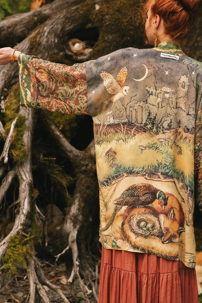 Model wearing a bamboo-viscose mid-length duster kimono robe where even the unlikeliest of friends...a fox and a pheasant...find warmth in each other’s company. Created in collaboration with Charles van Sandwyck - Market of Stars