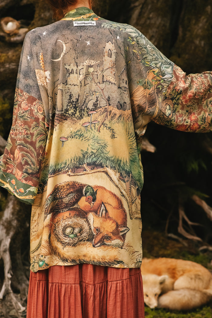 Model wearing a bamboo-viscose mid-length duster kimono robe where even the unlikeliest of friends...a fox and a pheasant...find warmth in each other’s company. Created in collaboration with Charles van Sandwyck - Market of Stars