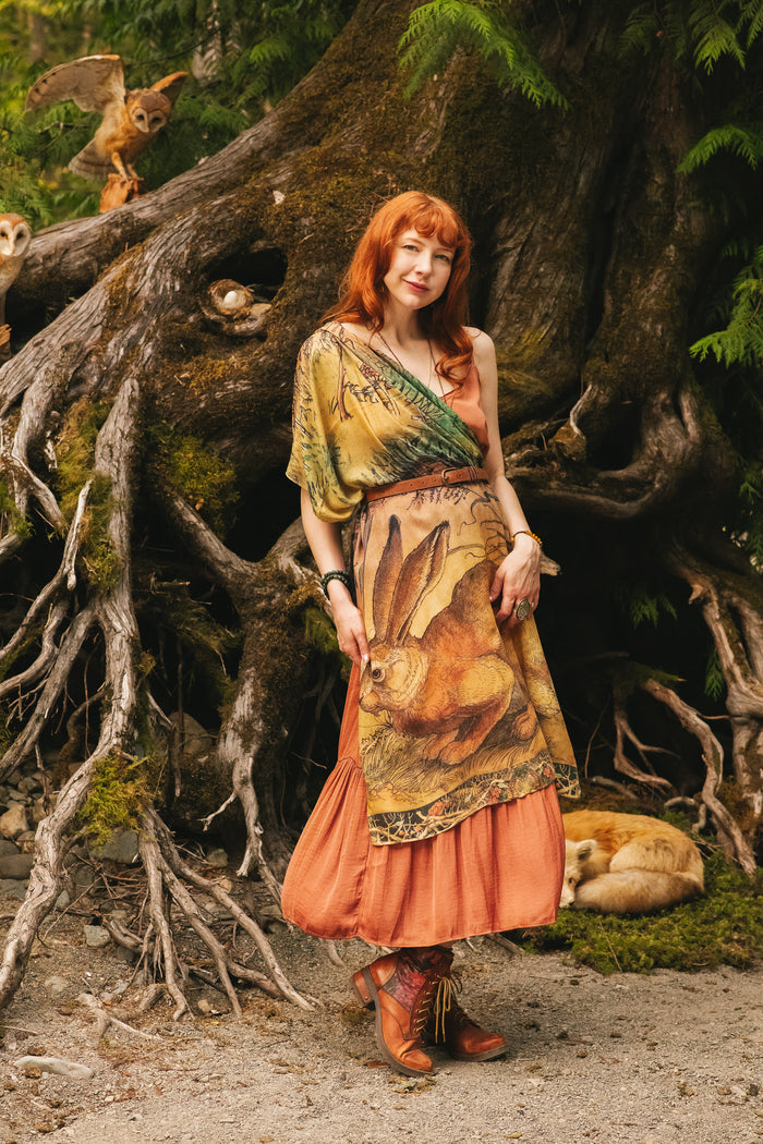 Model wearing a bamboo-viscose scarf where a noble rabbit rests deep within an underground burrow, surrounded by the warmth and safety of the earth. Created in collaboration with Charles van Sandwyck - Market of Stars