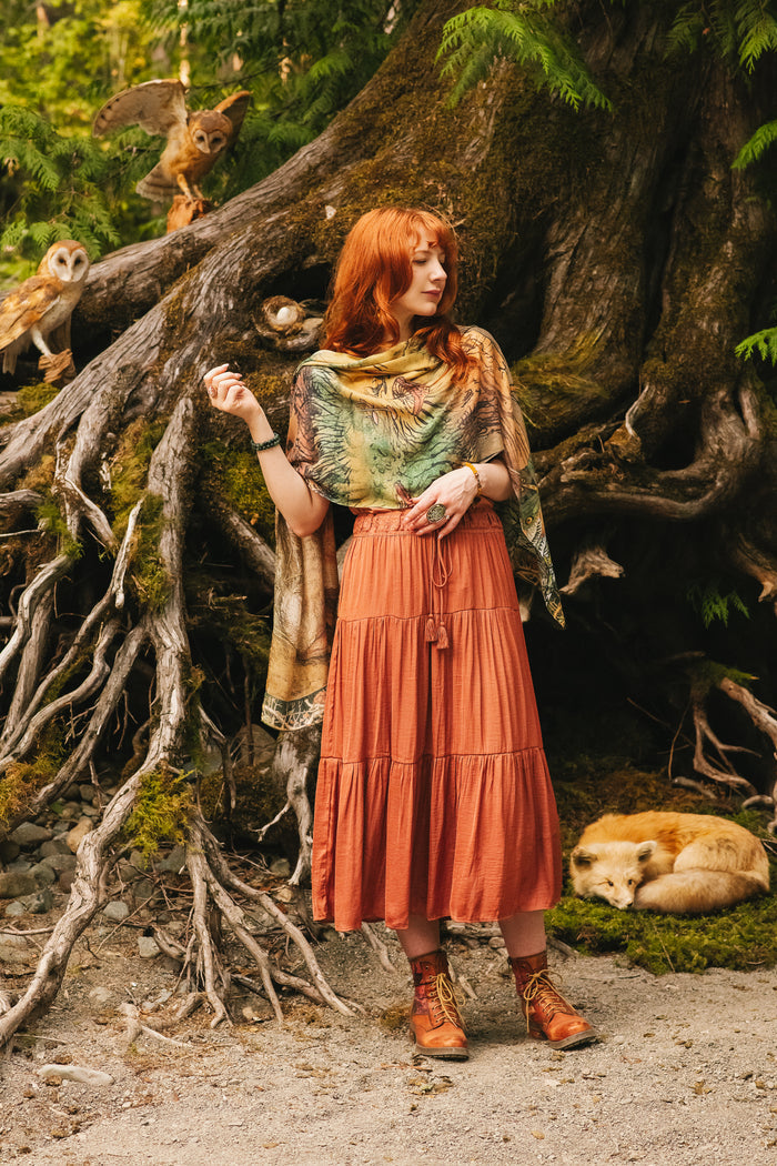 Model wearing a bamboo-viscose scarf where a noble rabbit rests deep within an underground burrow, surrounded by the warmth and safety of the earth. Created in collaboration with Charles van Sandwyck - Market of Stars