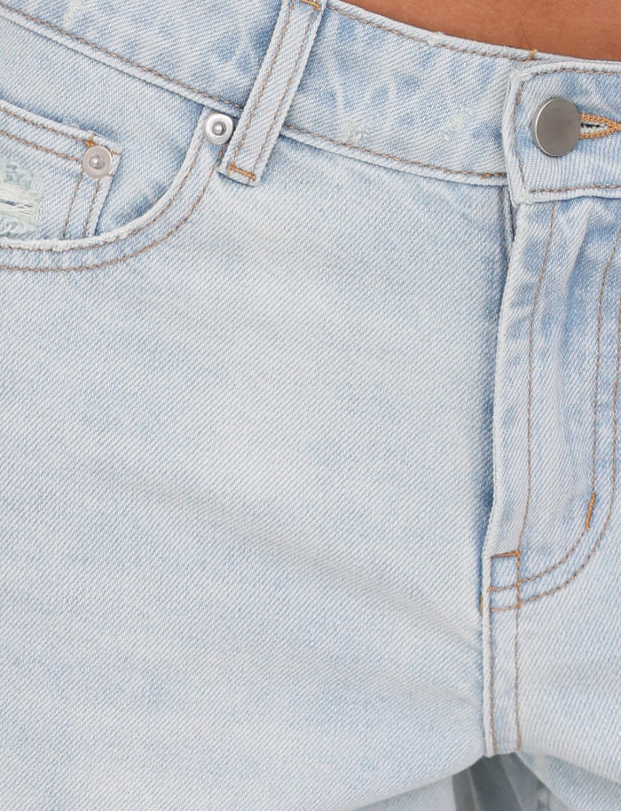 Close-up of the waist area of the TIGERMIST ZANDER SHORT - BLUE : LIGHT WASH, focusing on the top button, a partial view of the front pocket, and the belt loops. The fabric shows subtle faded creases and slight wear near the pocket.